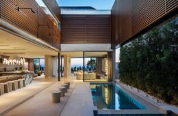 The interior pool courtyard at 3512 Ocean Boulevard in Corona del Mar at dusk, with slatted louvers above and the Pacific beyond