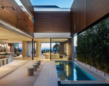 The interior pool courtyard at 3512 Ocean Boulevard in Corona del Mar at dusk, with slatted louvers above and the Pacific beyond
