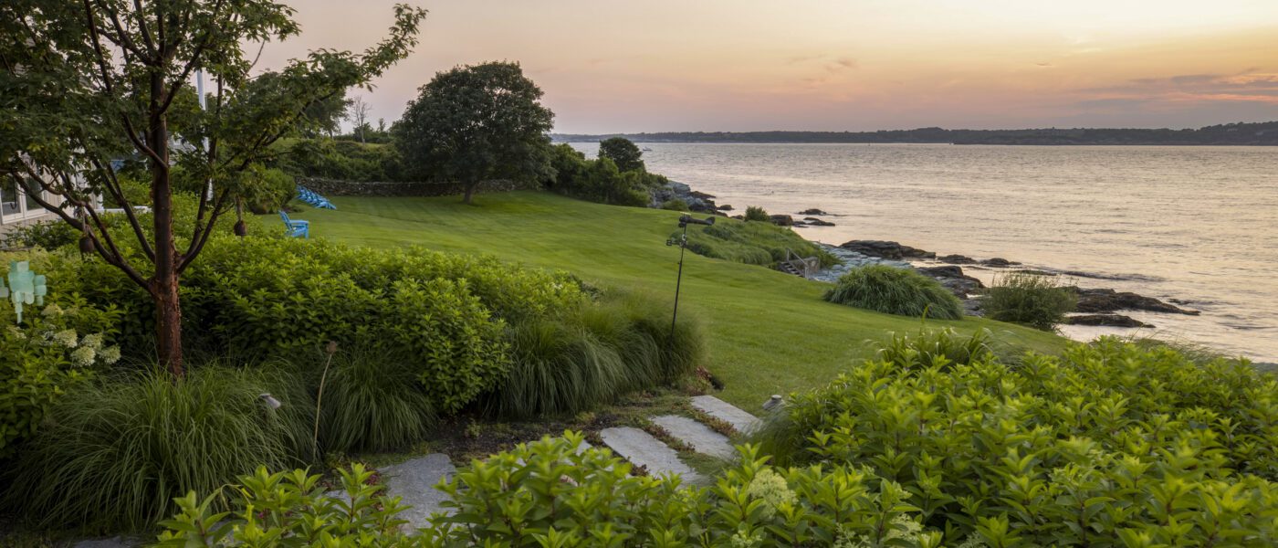 Hydrangea, grasses, and open lawn descend to the rocky Newport shoreline