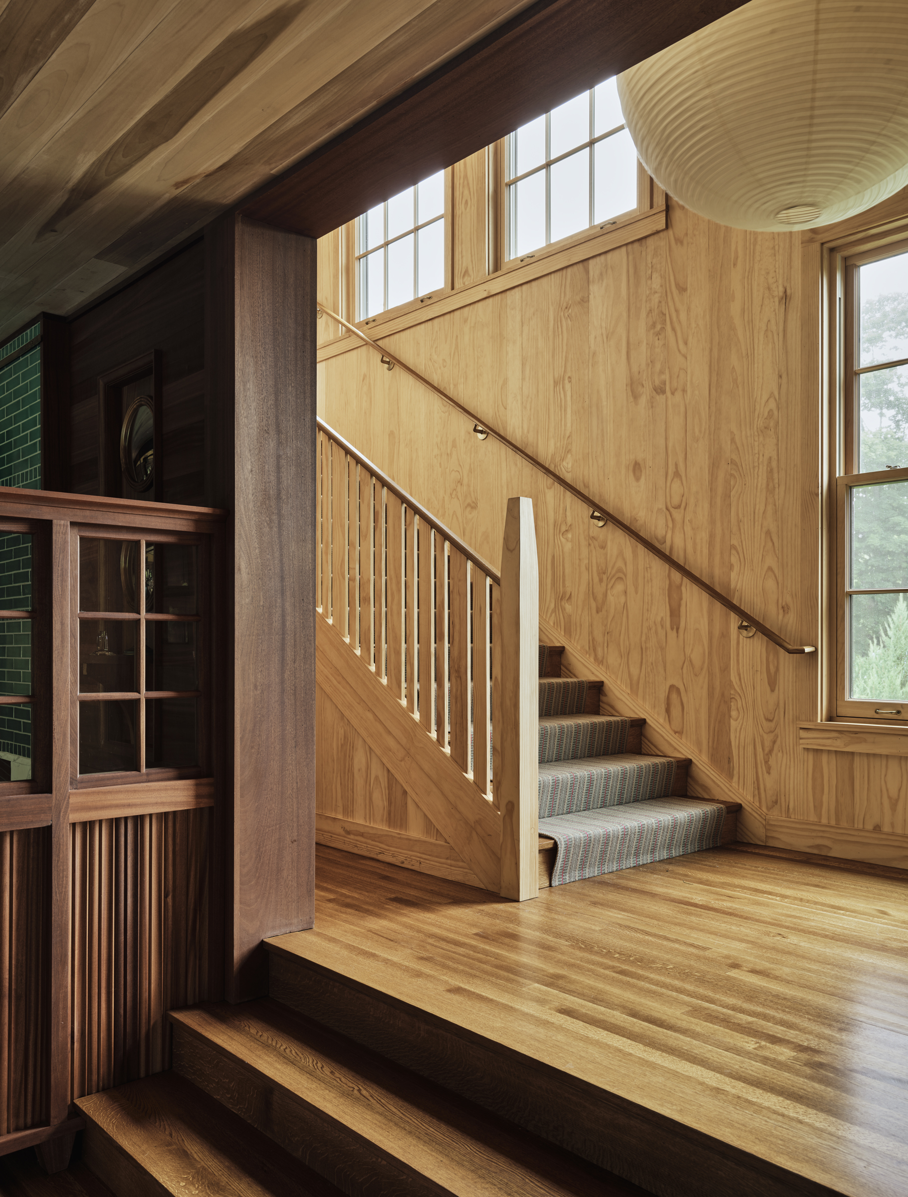 A wood stair rises against vertical pine boarding