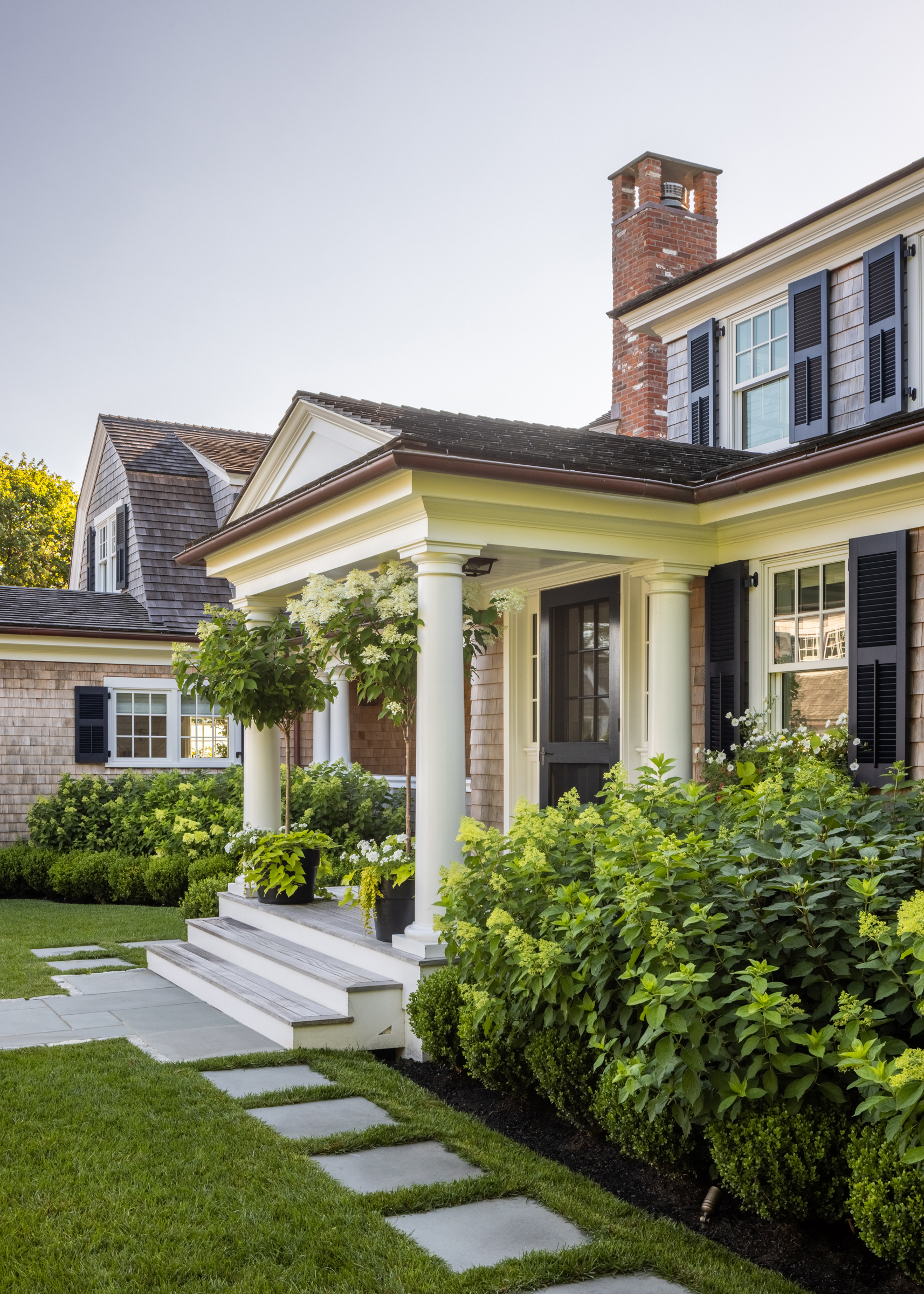 Bluestone treads cross the lawn toward the hydrangea-framed entrance of the Edgartown house
