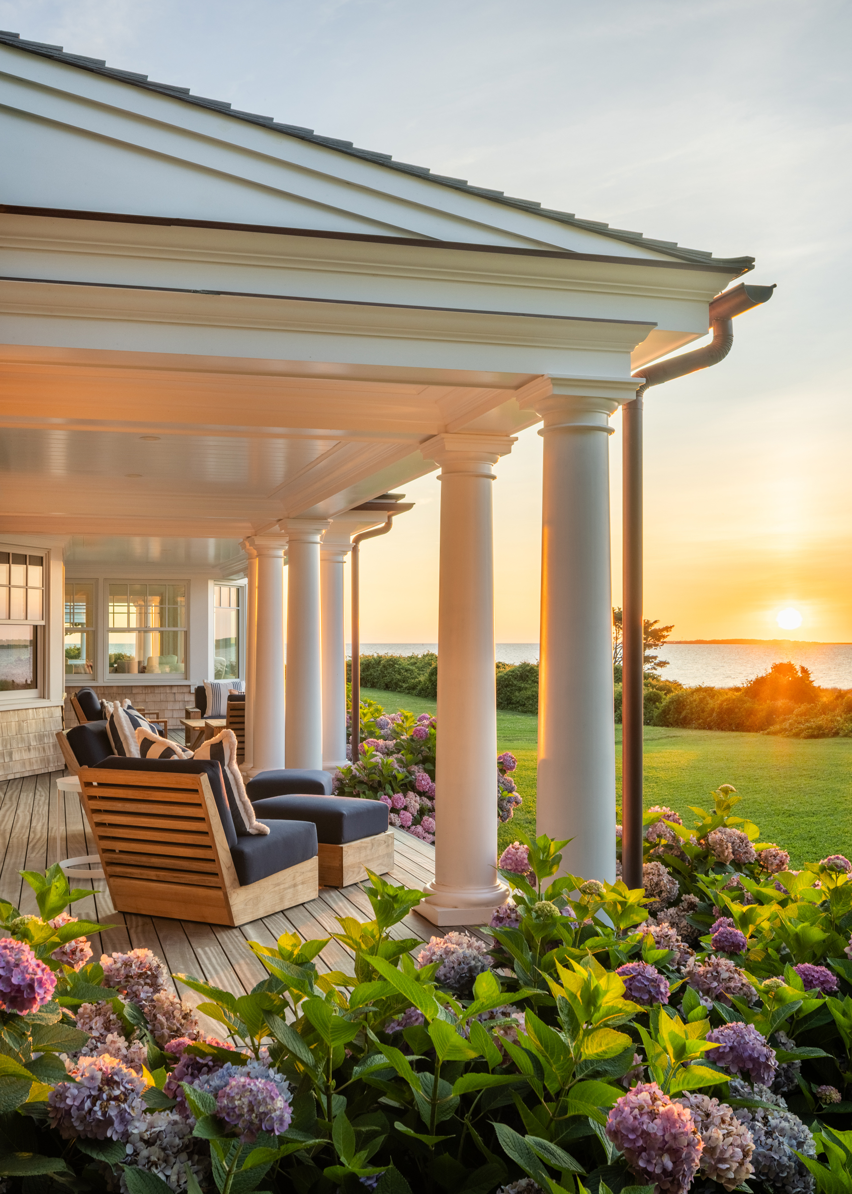Porch columns and hydrangeas frame sunset over the water in Edgartown