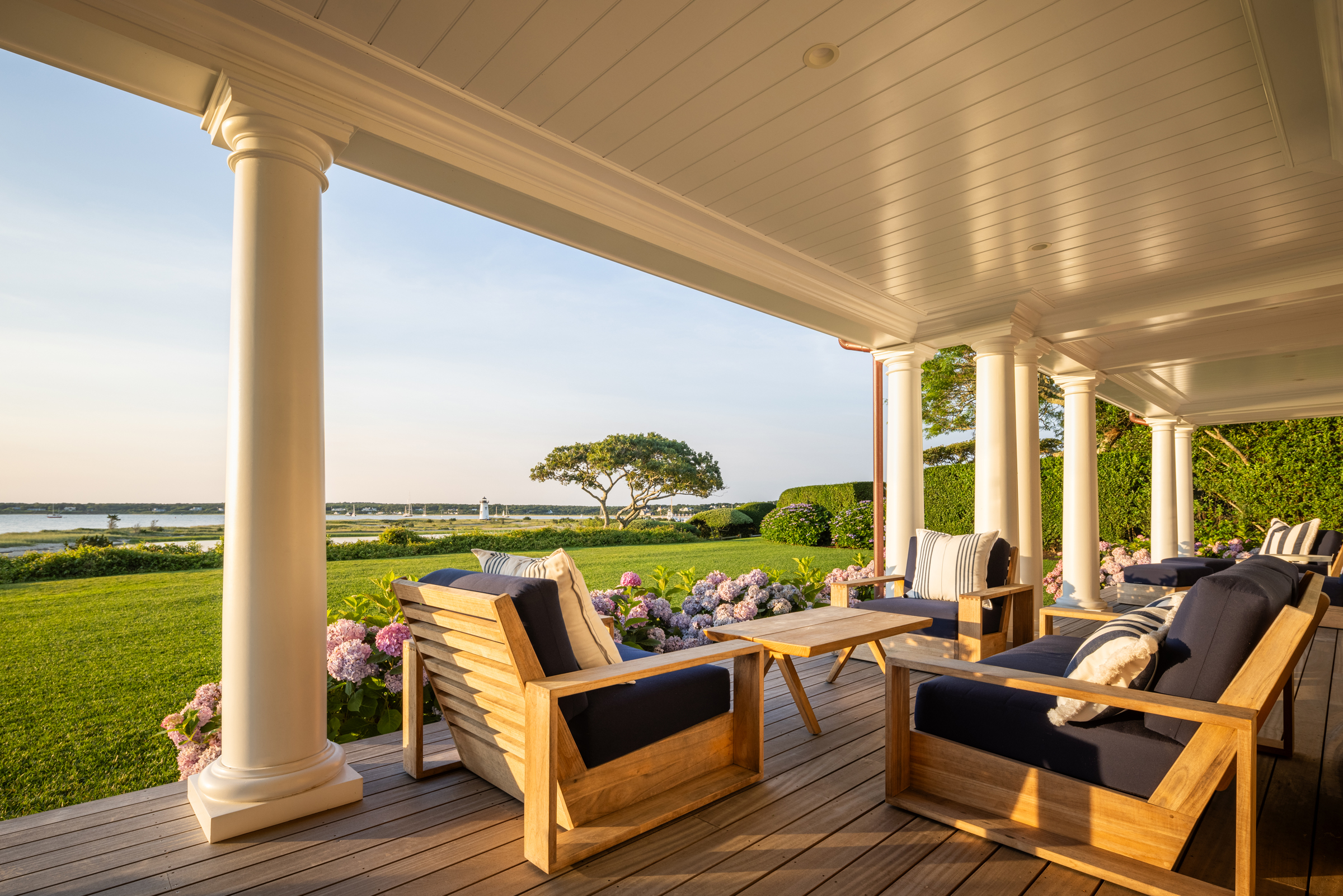 Teak seating on the deep waterfront porch overlooks the lawn, harbor, and Edgartown Lighthouse