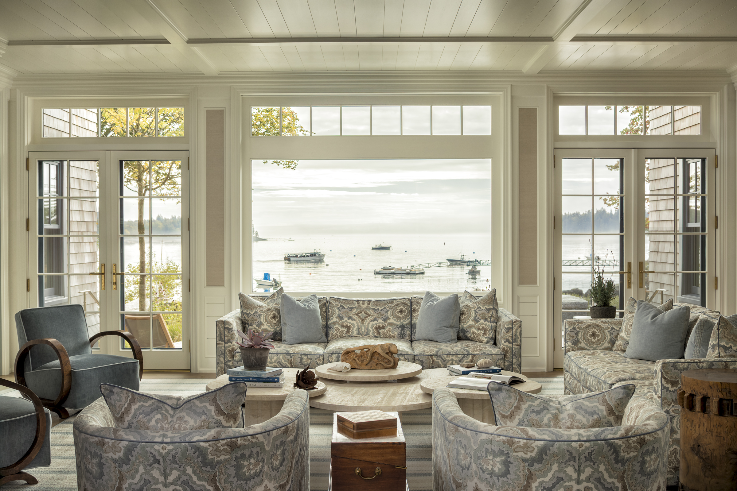 A soft blue and cream living room faces a large harbor-view picture window
