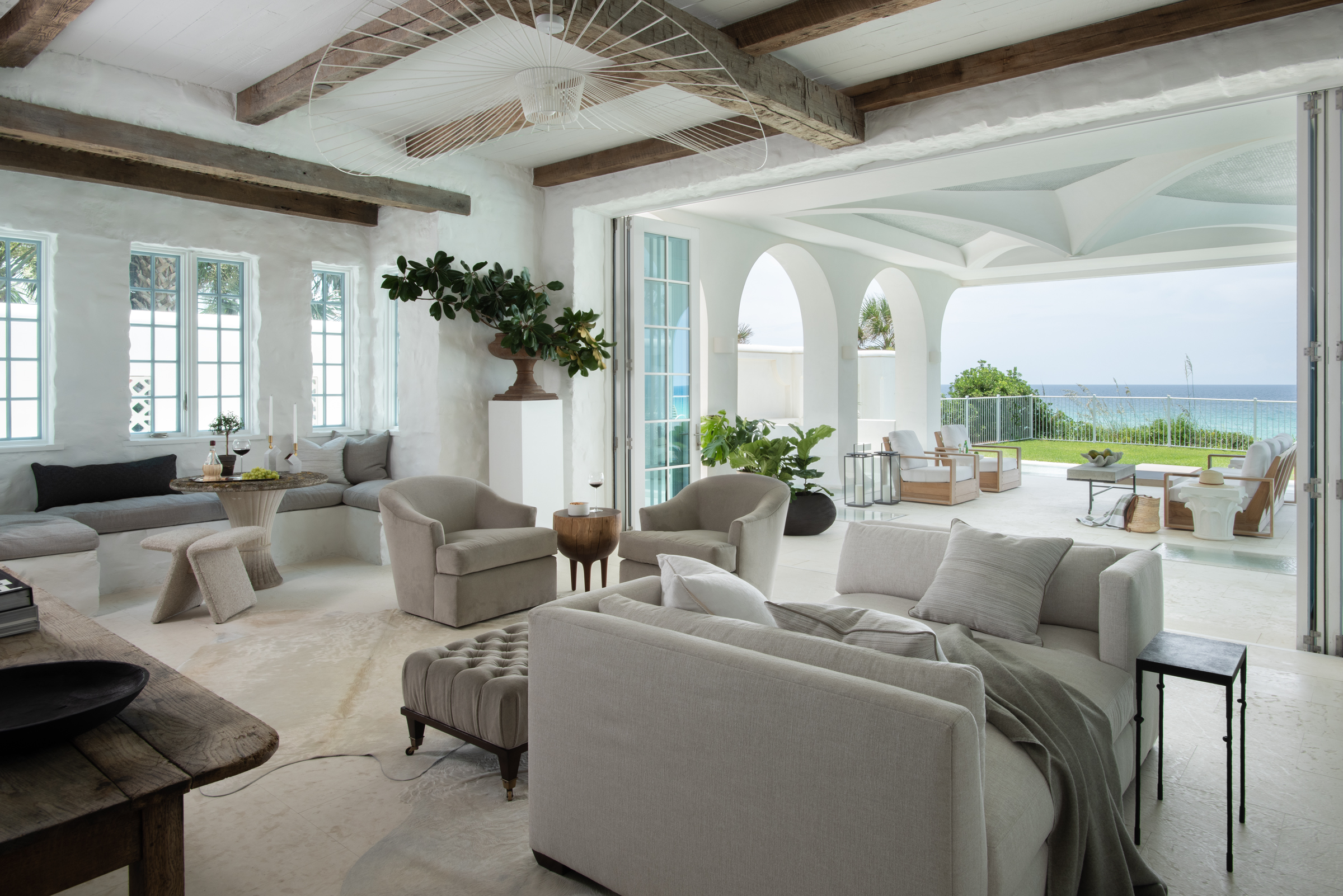 Folding doors connect a pale living room to a Gulf-front lanai