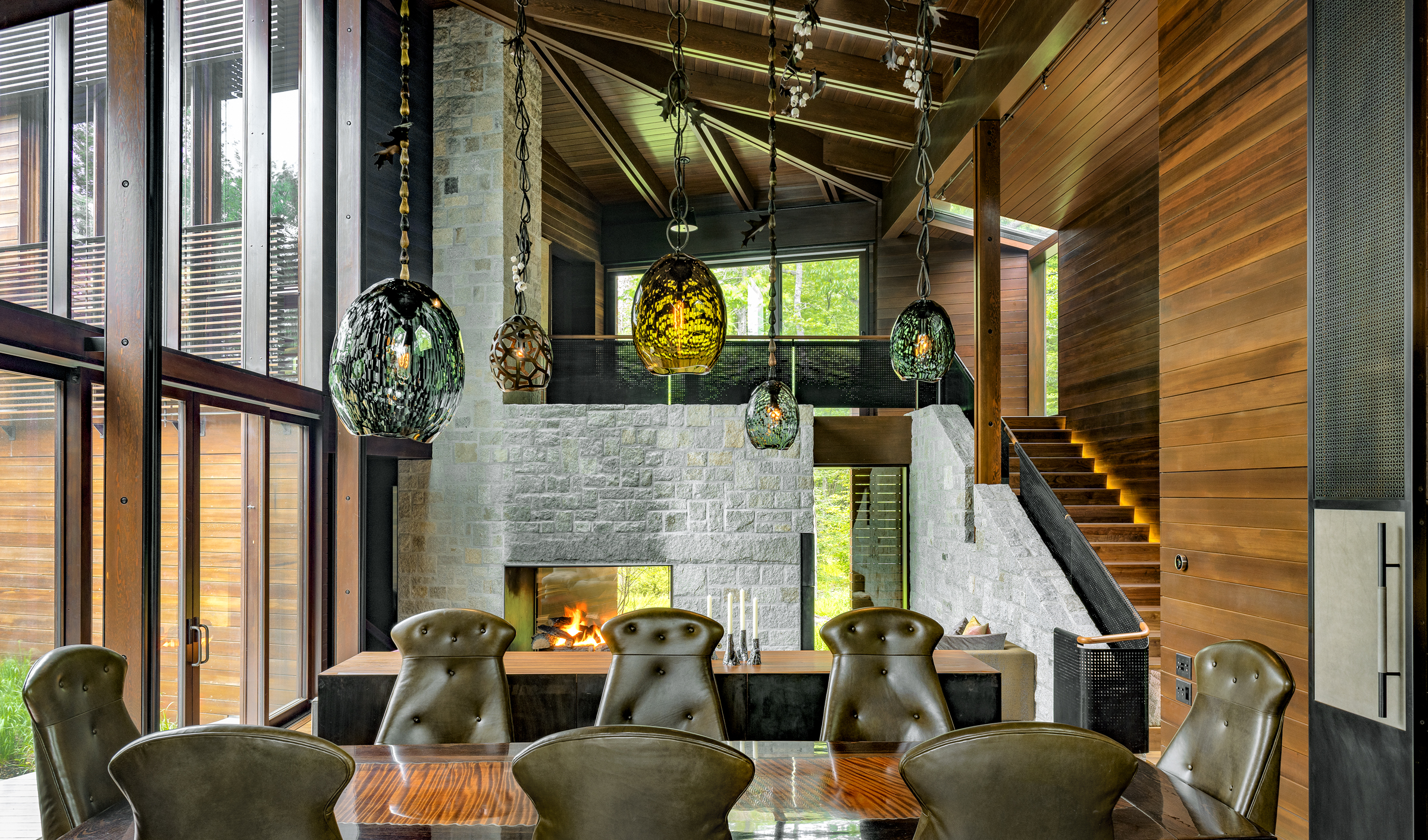 A monumental stone hearth anchors a tall cedar living and dining pavilion