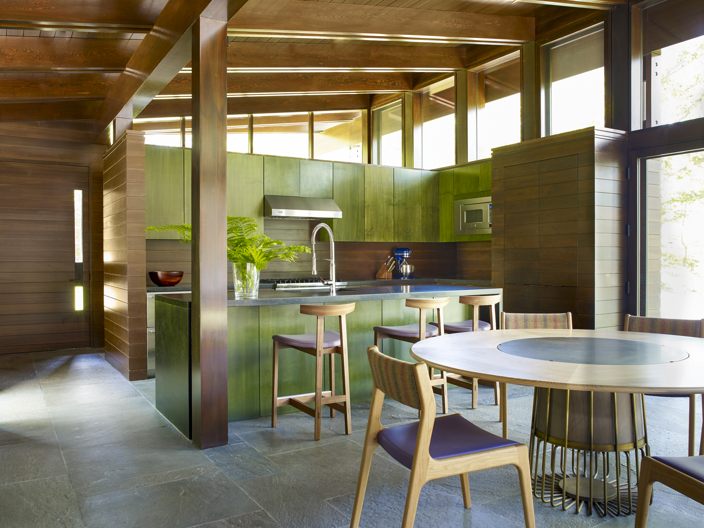 Patinated green cabinetry sits beneath an exposed cedar ceiling