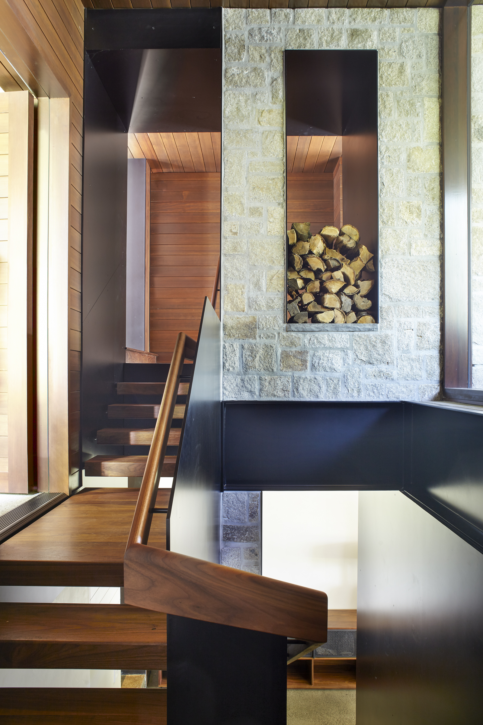 A niche in the stone chimney stores firewood beside a walnut stair