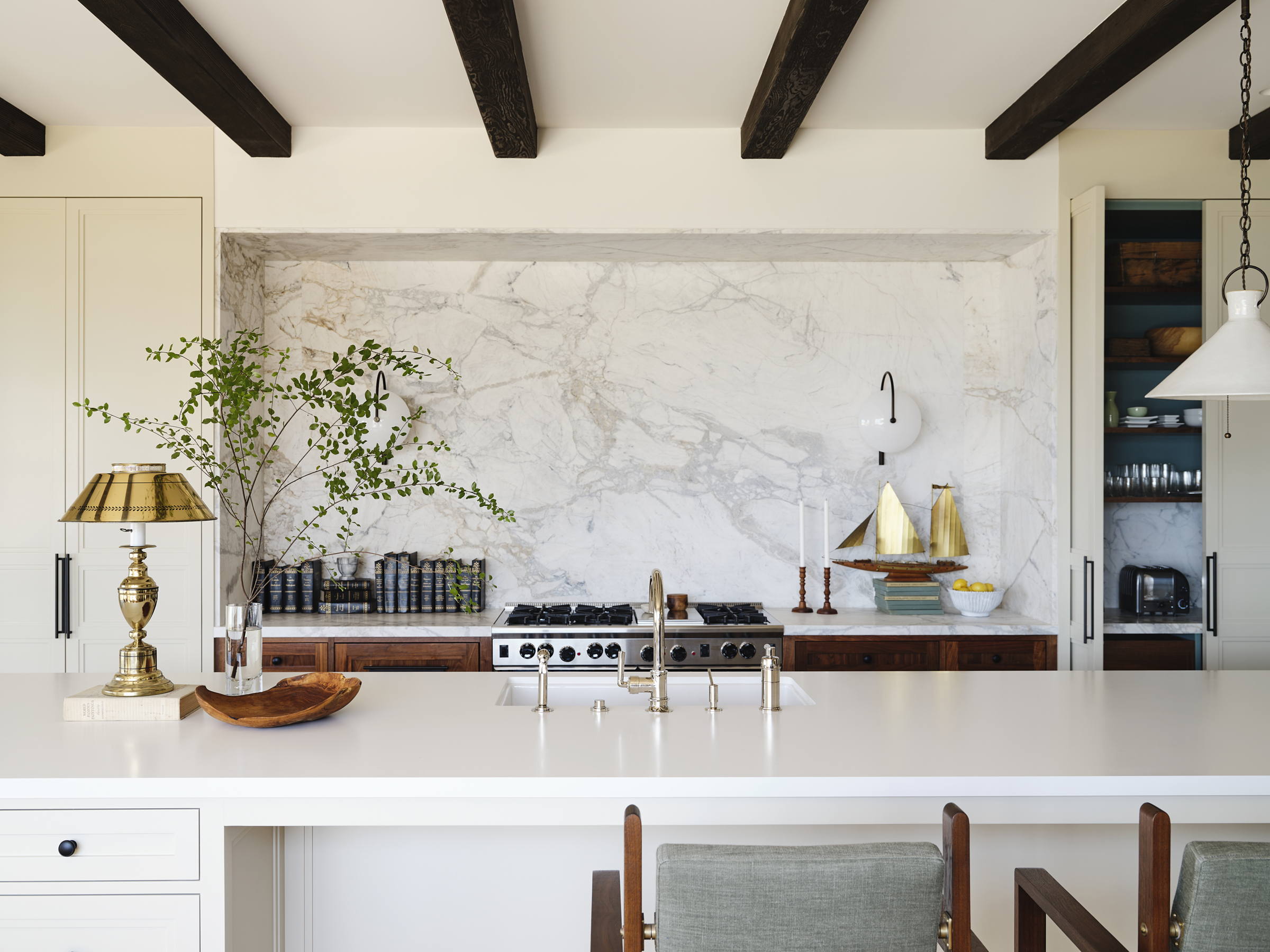 A furniture-like kitchen island faces a Calacatta Michelangelo Dolomite niche
