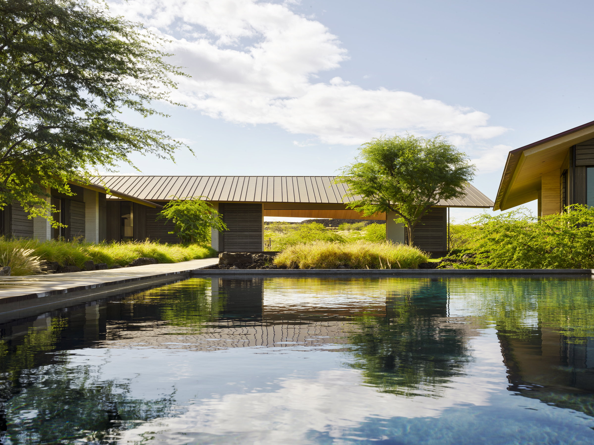 A long reflecting pool and central lawn organize low pavilions in a lava field