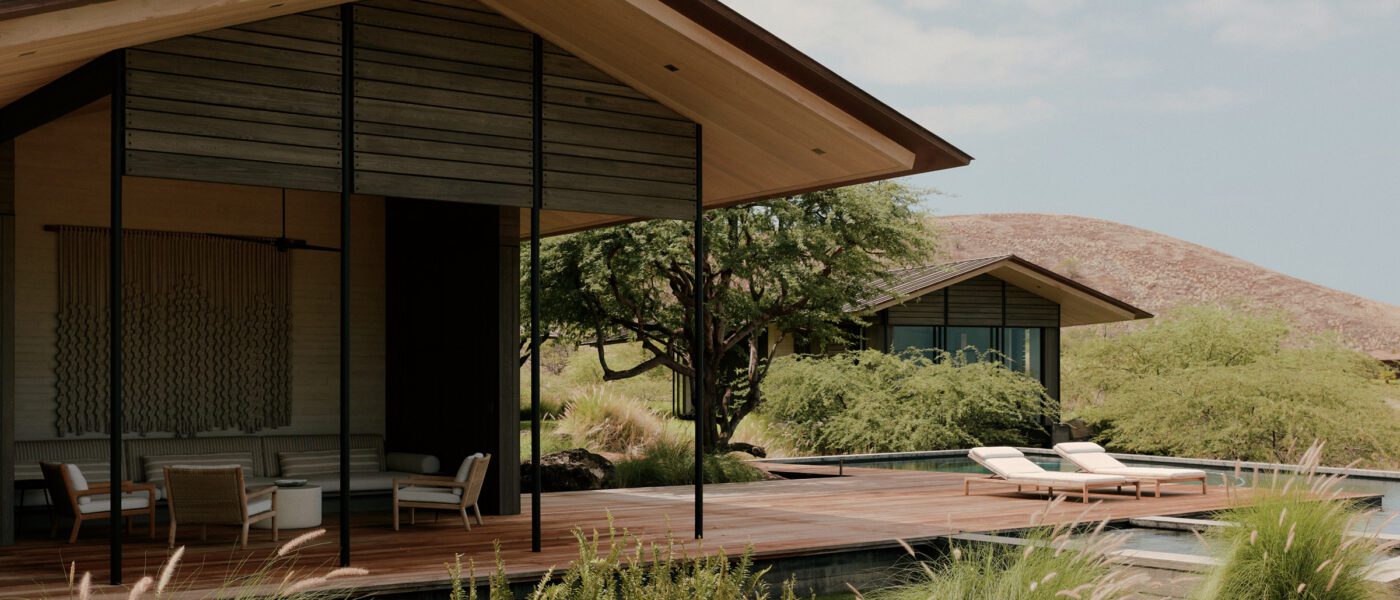 Deep eaves shelter an open-air pavilion surrounded by lava rock and native grass