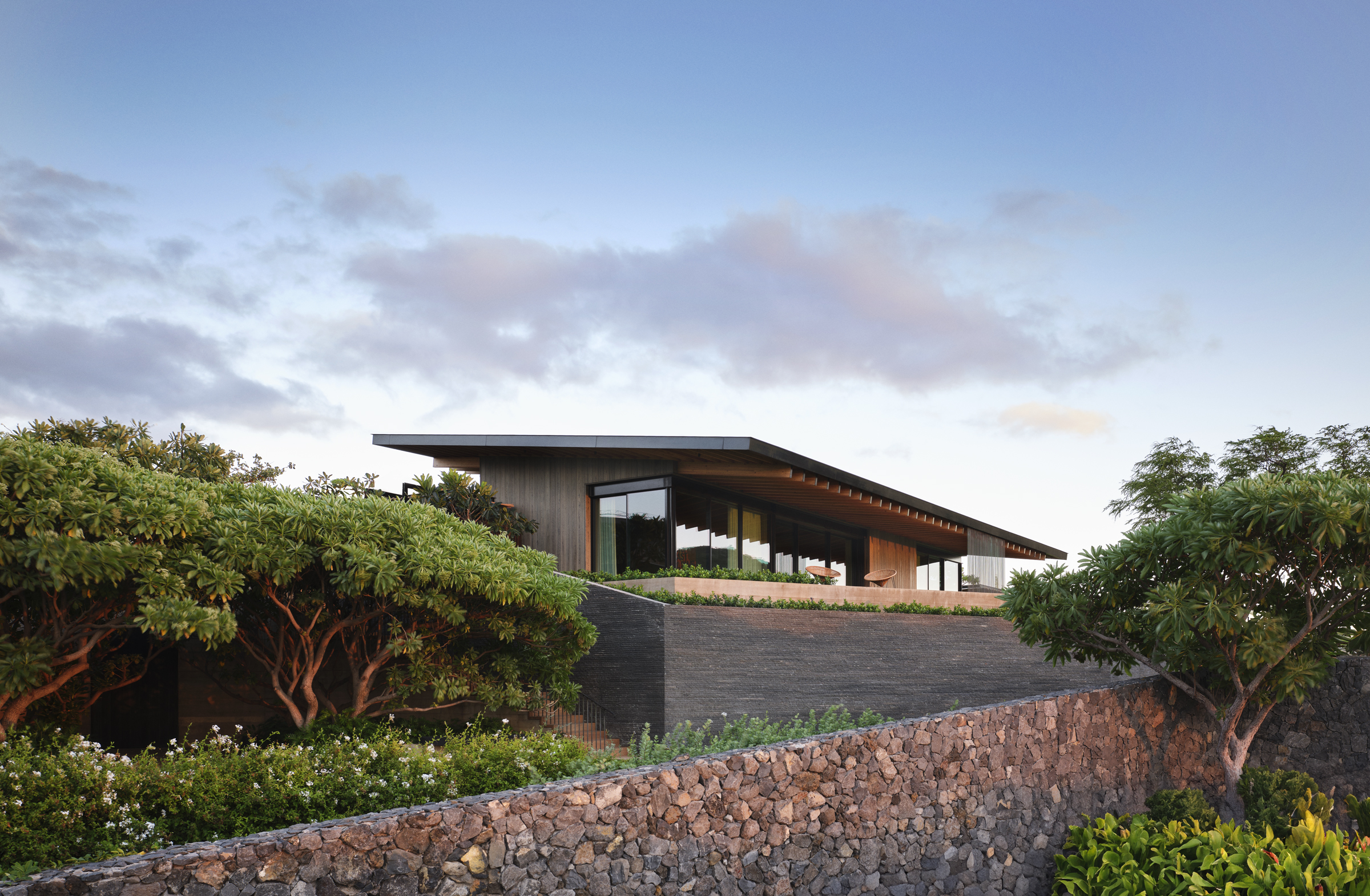 Stacked lava rock and concrete step the guest-house pavilions toward Makena Beach
