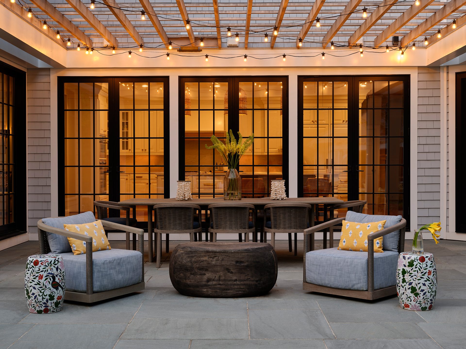 Covered patio at King’s Way with dining and lounge seating beneath an illuminated pergola