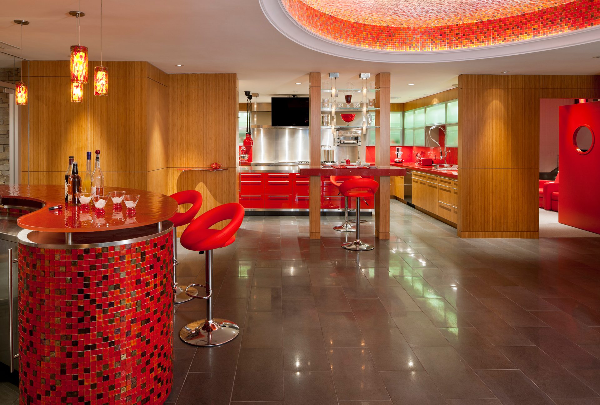 Laurel Woods test kitchen with stainless-steel appliances, red stools, and curved wood cabinetry