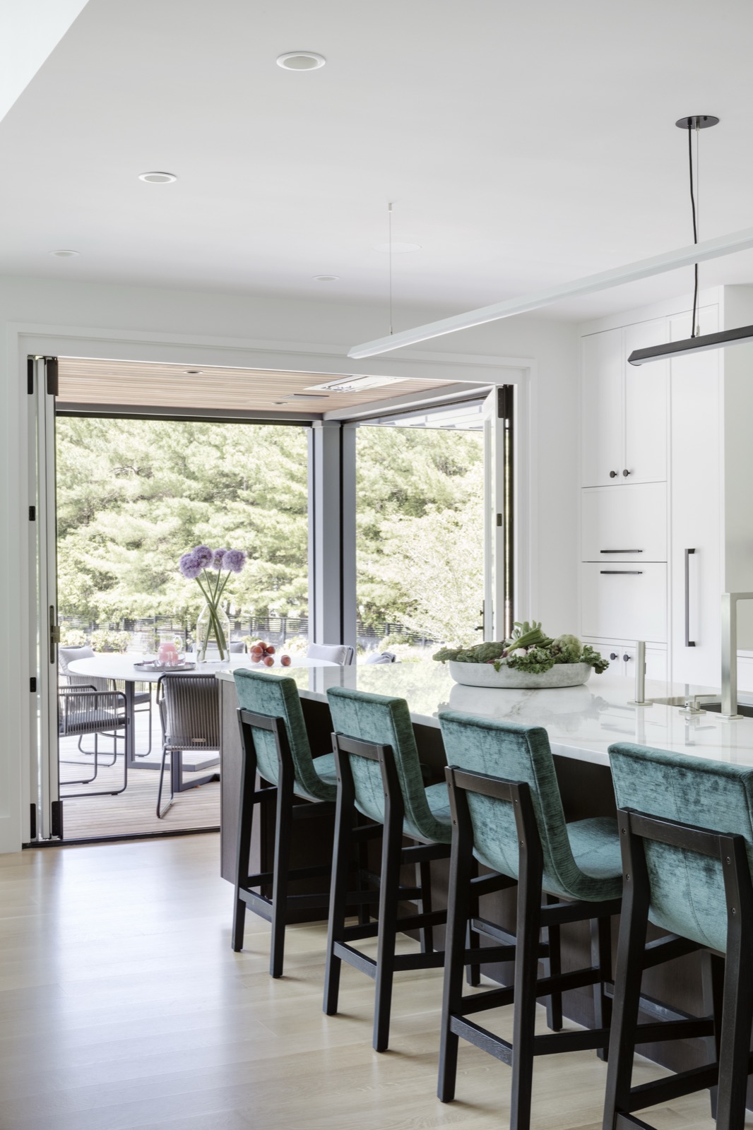 Terrace Edge kitchen island with velvet stools and doors opening to a covered dining terrace