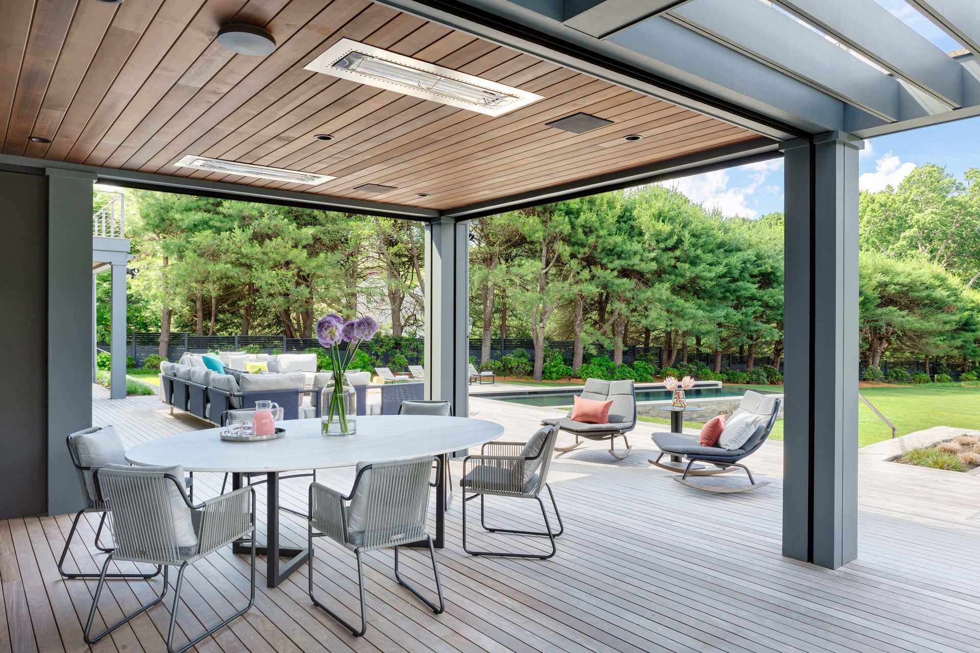 Covered dining terrace at Terrace Edge opening toward the pool and wooded landscape