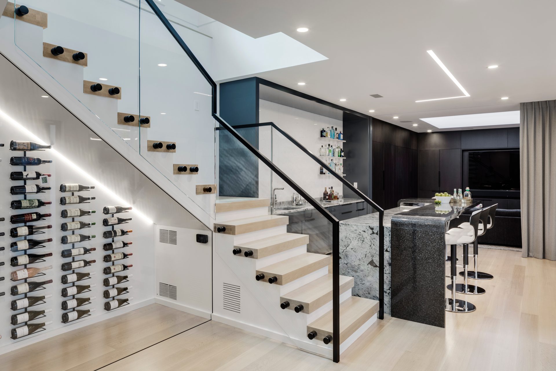 Floating stair with glass railings beside wine storage and a bar at Terrace Edge
