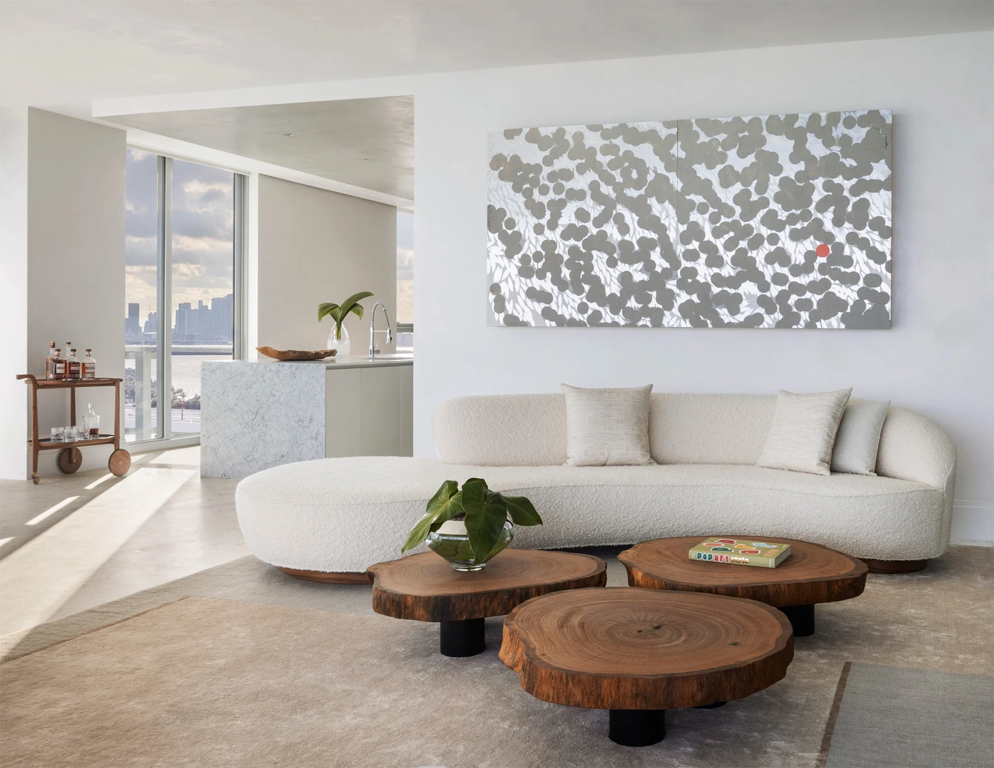 Light-filled living room by Andre Kikoski Architecture with a curved sofa and sculptural wood tables